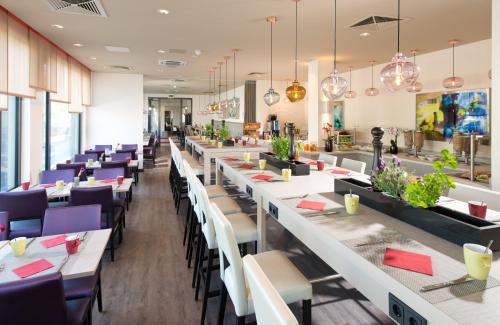 慕尼黑慕尼黑市奥林匹克公园莱昂纳多酒店的餐厅配有白色桌子和紫色椅子