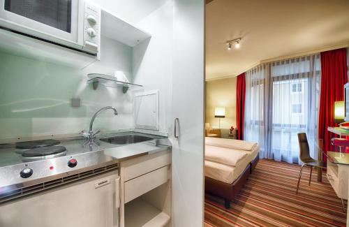 慕尼黑慕尼黑莱昂纳多酒店的一个带水槽的厨房和一张位于客房内的床