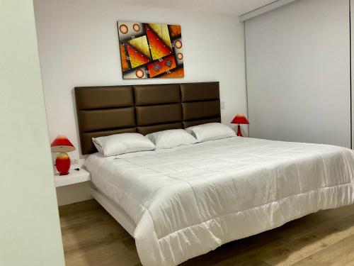 帕拉卡斯Solymar Beach House - Paracas的卧室配有一张白色大床,墙上挂有绘画作品