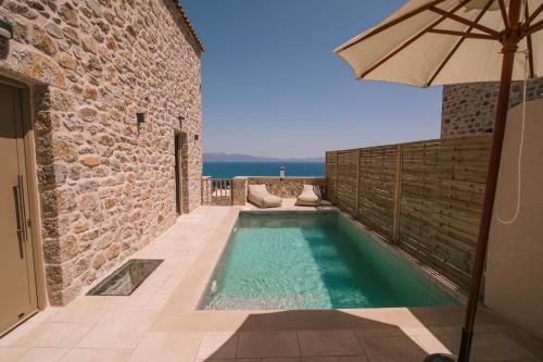 伊西翁Mani Luxury Suites and Studios in Gytheio with Private Pools的一座带遮阳伞的游泳池位于大楼旁