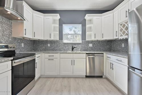 杰克逊维尔The Jewel of Jacksonville的厨房配有白色橱柜和不锈钢用具