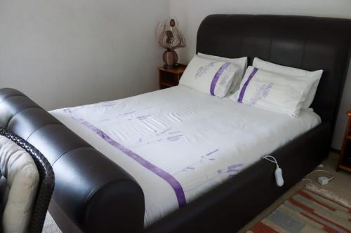 约翰内斯堡Bougainvillea at Boskruin的一张黑色床,配有紫色床单和枕头