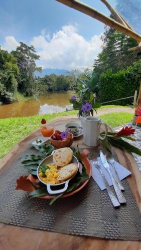 瓜杜阿斯Aguas Claras Bamboo Ecolodge的一张早餐桌,上面有一盘食物和一条河流