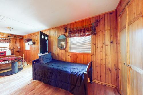 加特林堡Tweeting Brook的卧室配有木墙内的一张床