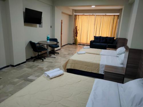 瓜亚基尔OCEANIk SUITES & HOTEL的酒店客房设有两张床、一张沙发和一张桌子。