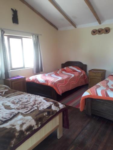 Isla de SolInka Wasi的一间卧室设有两张床和窗户。