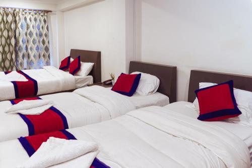 巴克塔普尔Sweet Inn的一间设有4张床及红色和蓝色枕头的客房