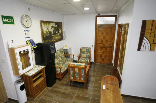 阿利坎特圣费尔南多旅馆 的一间设有椅子和墙上的时钟的房间