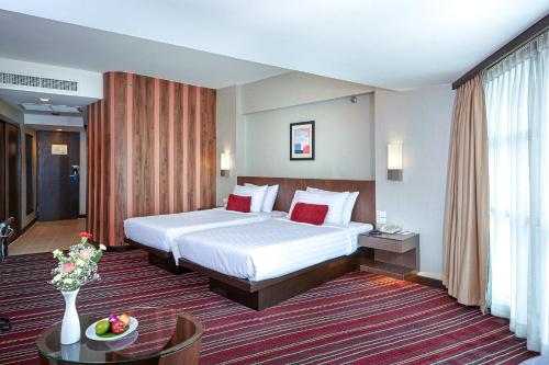曼谷曼谷大使酒店的酒店客房配有一张床铺和一张桌子。