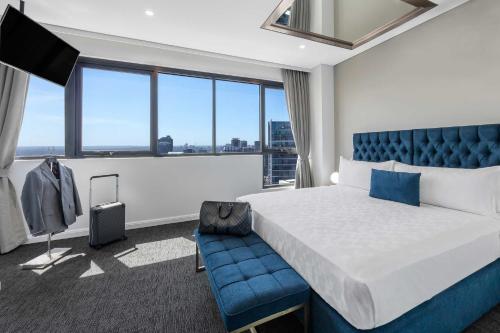 悉尼Meriton Suites Kent Street, Sydney的酒店客房,配有一张床和一张蓝色椅子