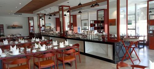 马德望V V Hotel Battambang的餐厅设有长长的酒吧,配有橙色椅子
