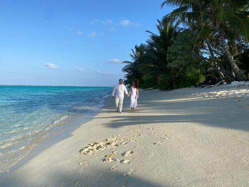 图杜Thoddoo Haisha inn, Maldives的海滩上行走的男人和女人