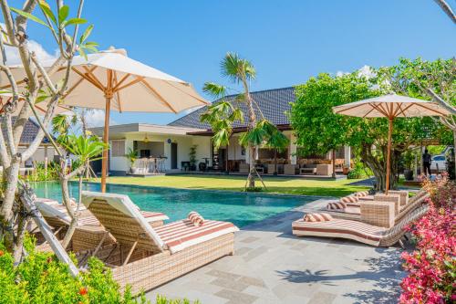 努沙杜瓦Green D'Mel Luxury Homestay的一个带躺椅和遮阳伞的游泳池