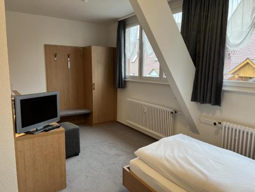 菲林根-施文宁根Hotel Bären的一间卧室设有一张床、一台电视和楼梯。