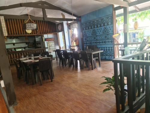 科隆Coron town travellers inn的餐厅铺有木地板,配有桌椅