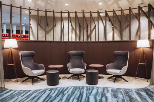 格拉特布鲁格多林特机场苏黎世酒店的一间等候室,配有三把椅子和两张桌子