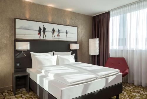 格拉特布鲁格多林特机场苏黎世酒店的卧室配有一张白色大床和红色椅子