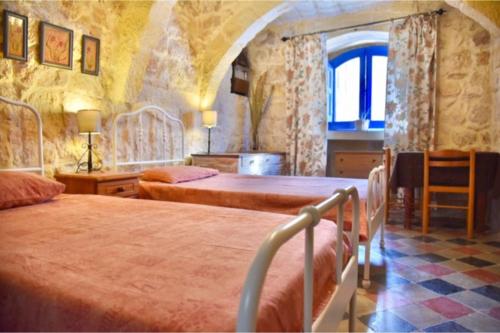 休吉让Ta'Martin Farmhouse Xewkija Gozo的一间卧室设有两张床和窗户。