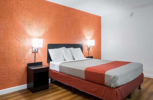 Prospect Heights展望高地6号汽车旅馆的一间卧室配有一张带橙色墙壁的大床
