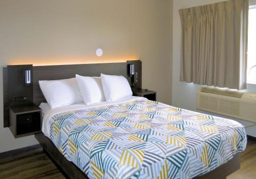 里诺里诺牲畜活动中心6号汽车旅馆的一间卧室配有一张大床和色彩缤纷的被子