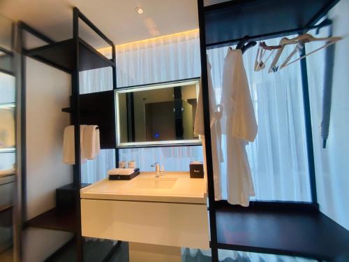 广义NEWCC HOTEL AND SERVICED APARTMENT的一间带水槽和镜子的浴室