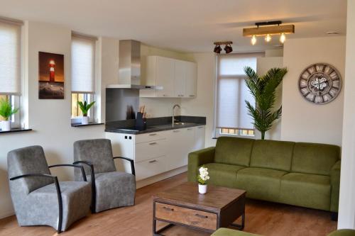 佐特兰德Luxe vakantievilla Zoutelande的一间带绿色沙发的客厅和一间厨房