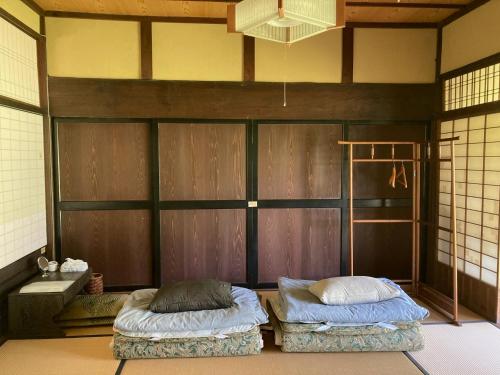 Ayabe一汁一菜の宿　ちゃぶダイニング Ichiju Issai no Yado Chabu Dining Unforgettable Farmstay experience in Deep Kyoto的一间设有两张床铺的客房,位于一个墙上