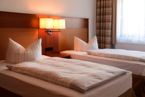 苏尔Olympia Hotel Suhl的酒店客房设有两张床和窗户。