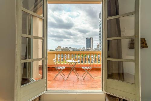 巴塞罗那Casa Gracia Apartments的阳台的开放式窗户配有桌椅