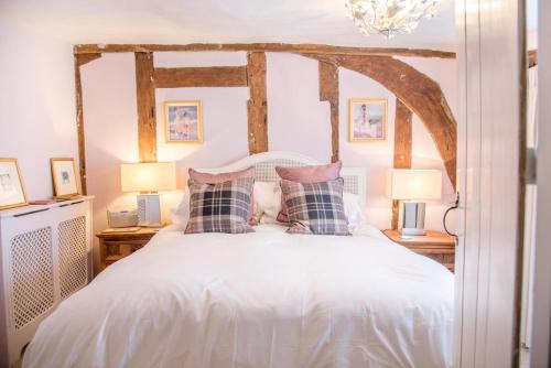 拉文纳姆Rose Cottage in Lavenham的卧室配有带枕头和两盏灯的白色床。