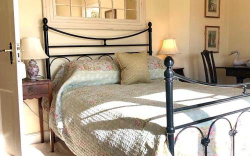汤顿Farthings Country House Hotel & Restaurant Tunton的一间卧室配有一张床、两盏灯和一个窗户。