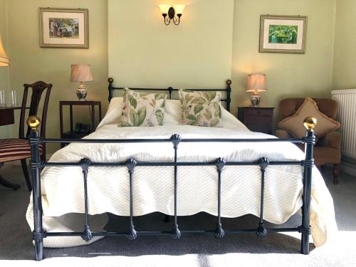 汤顿Farthings Country House Hotel & Restaurant Tunton的一间卧室配有一张床、两把椅子和两盏灯。