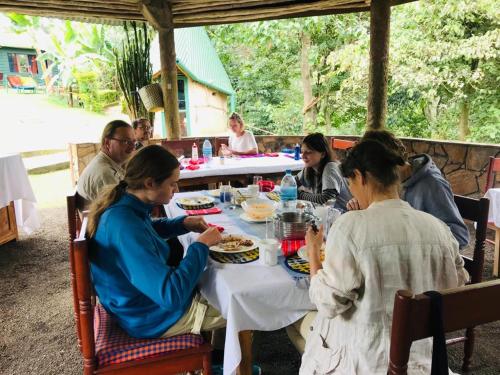 阿鲁沙Songota Falls Lodge的一群坐在桌子旁吃饭的人