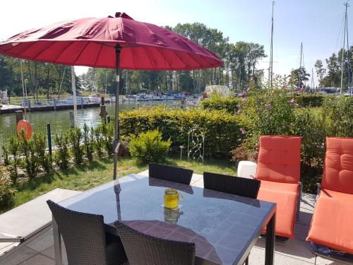 于克里茨Kapitänsresidenz - Haus direkt am Wasser的露台上的一张桌子和一把红色遮阳伞