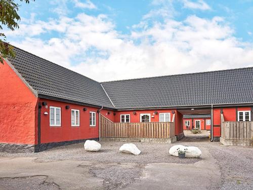 奥基克比5 person holiday home in Aakirkeby的一座红色的建筑,前面有三块岩石
