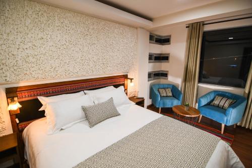 乌尤尼Cielo & Sal Hotel的酒店客房,配有一张床和两张蓝色椅子