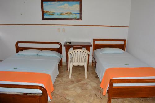 Puerto BerríoHotel Tayrona的配有一张桌子和一把椅子的客房内的两张床