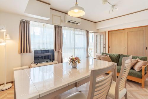 大阪环球湾公寓式酒店的厨房以及带桌子和沙发的客厅。