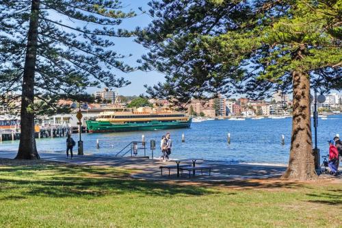 悉尼Best location in Manly Harbour view的水上的船只,人们在公园里散步
