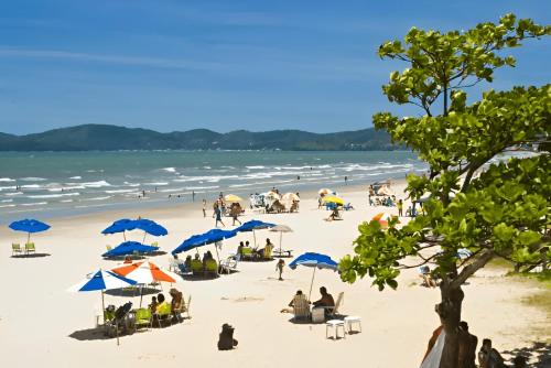 伊塔佩马APT Praia Central Itapema 90MTS do Mar的一群人,在海滩上,用蓝伞