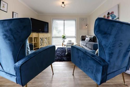 戴尔斯福特Hidden Gem ~ Luxury Cottage near Lake Daylesford的客厅配有2把蓝色椅子和1张沙发