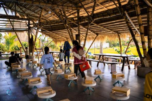 Dak LakLang's Pá Mé - Homestay - Bungalow - Camping Krông Pắk, Buôn Mê Thuột, Đắk Lắk, Việt Nam的一群人站在带桌椅的房间