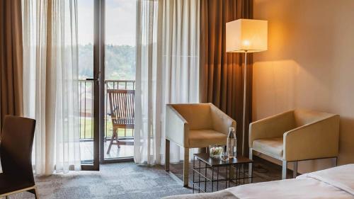 博德森特克索特利尔欧里米尔温泉酒店的酒店客房设有一张床铺和两张椅子以及一个阳台。