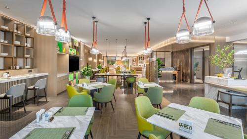 长沙长沙马栏山假日酒店的一间设有绿色桌椅的餐厅和一间酒吧
