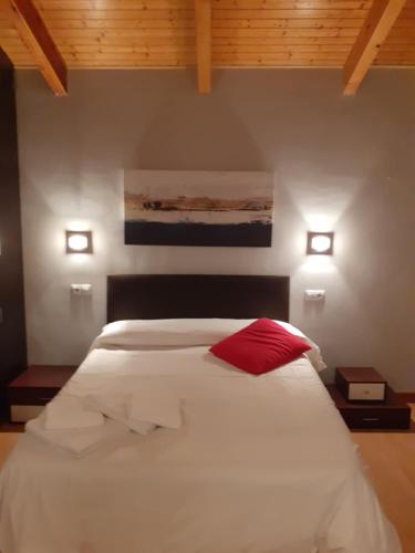 罗德里戈城Ciudad Rodrigo La Casa Azul的卧室配有白色的床和红色枕头