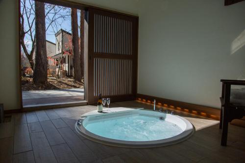 富士河口湖Glamping Villa Hanz Kawaguchiko的一个带大窗户的客房内的按摩浴缸
