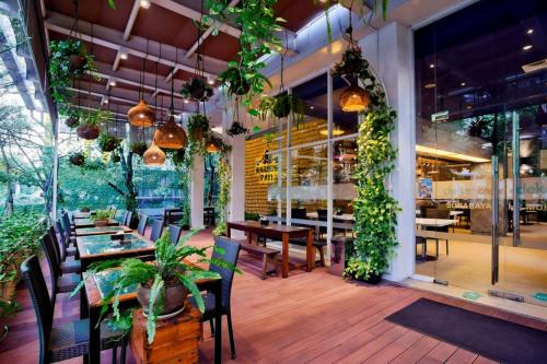 泗水Deka Hotel Surabaya HR Muhammad的一间设有桌椅的餐厅,种植了植物