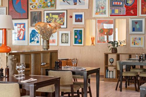 兰德维特Landvetter Airport Hotel, Best Western Premier Collection的餐厅设有桌椅,墙上挂有绘画作品