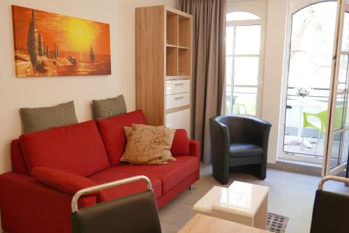 巴贝Haus Meeresblick - Ferienwohnung Sunrise A 2.18 (Ref. 128701)的客厅配有红色的沙发和椅子