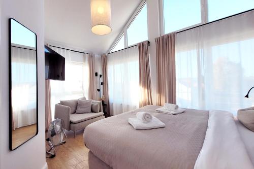 希尔克道夫Große Penthouse Ferienwohnung mit Meerblick, Sonnenterrasse & Luxusbad - Nur 50 Meter zum Strand的一间卧室配有一张床、一把椅子和窗户。